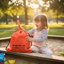 Petite fille au parc avec le sac à dos cordelette imperméable modèle 750 PROS Wear orange tissu PVC pour transport d'affaires de loisir résistant au sable