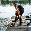 Pêcheur enfilant des chaussettes thermiques mi-hautes noires KL09/L PROS-Wear dans ses cuissardes pour une isolation optimale des pieds au sec.